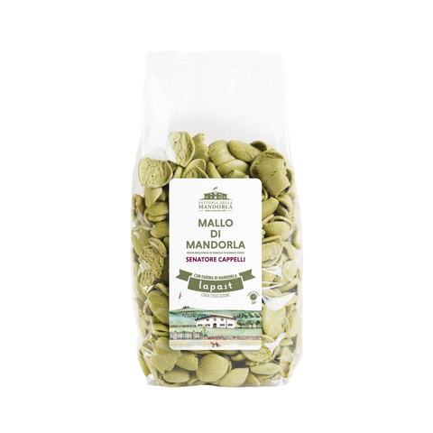 Pasta bio al mallo di mandorla servita in una ciotola con ingredienti vegetali su tavolo in legno