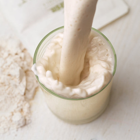 Bicchiere di latte di mandorla con mandorle pelate e mandorle sgusciate su tavolo in legno