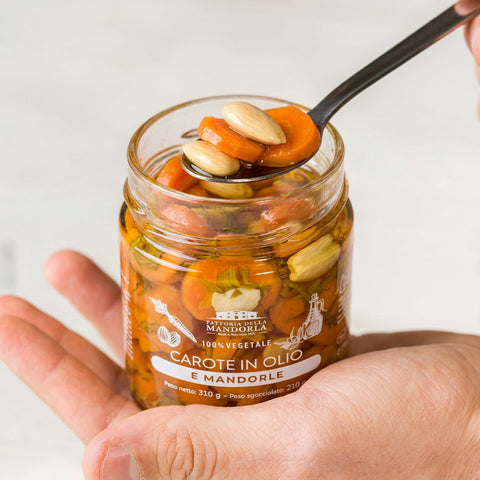 CAROTE IN OLIO DI MANDORLA BIO - 310g — vasetto aperto in mano con cucchiaio